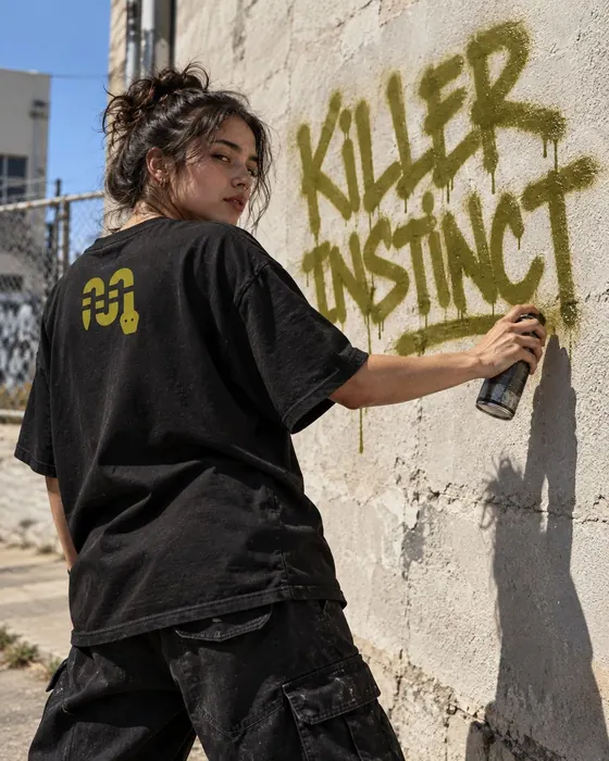 Ragazza che scrive Killer Instinct con la bomboletta su un muro
